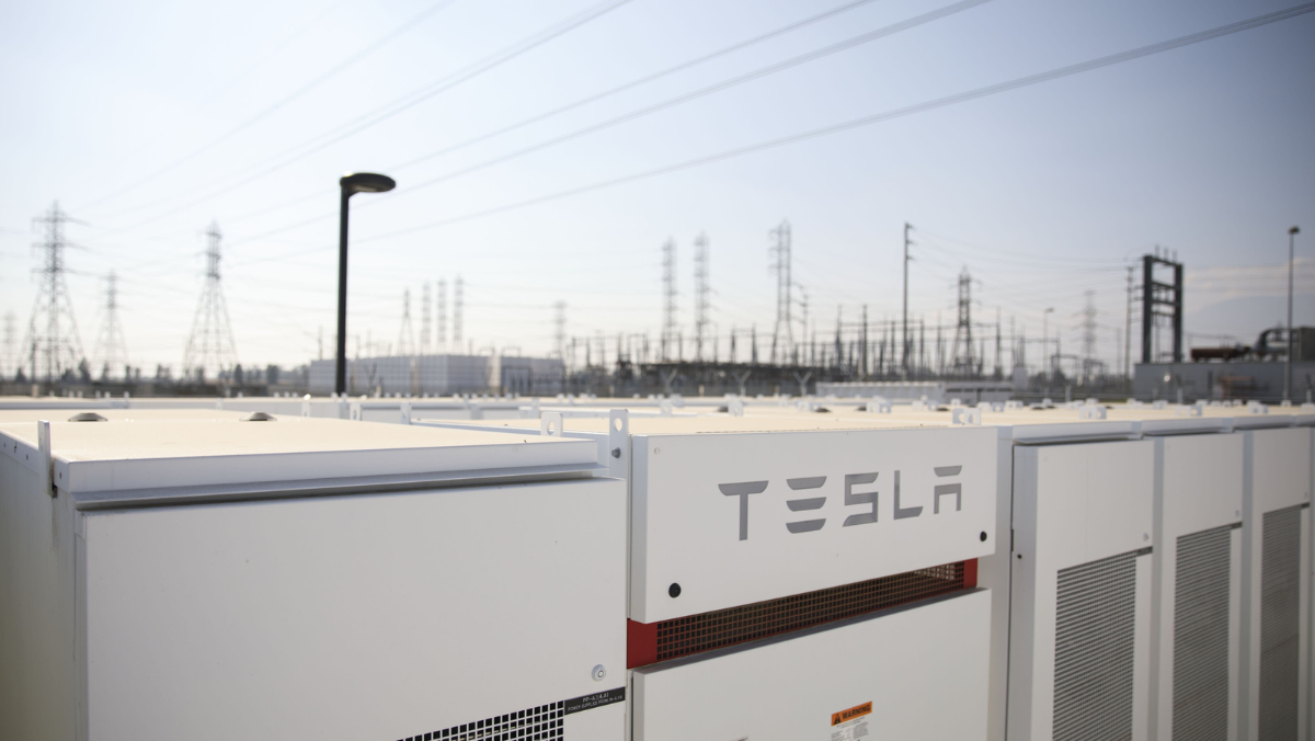 Tesla energy storage units installed near a field of power lines and electrical infrastructure